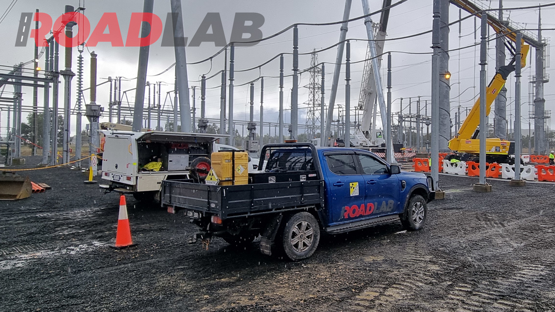 An electrical transformer yard, with a roadlab ute in the foreground and two cranes working behind it.