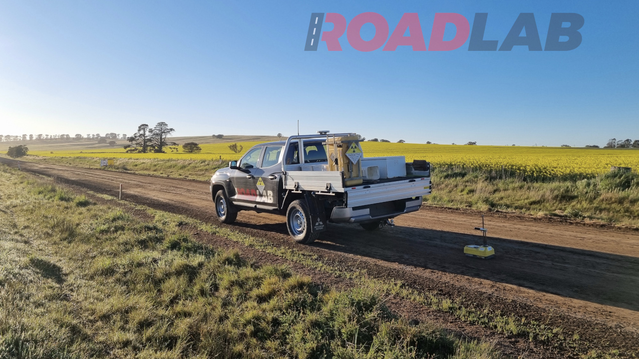 A ute on an unsealed road in the countryside, with a density gauge testing the pavement.